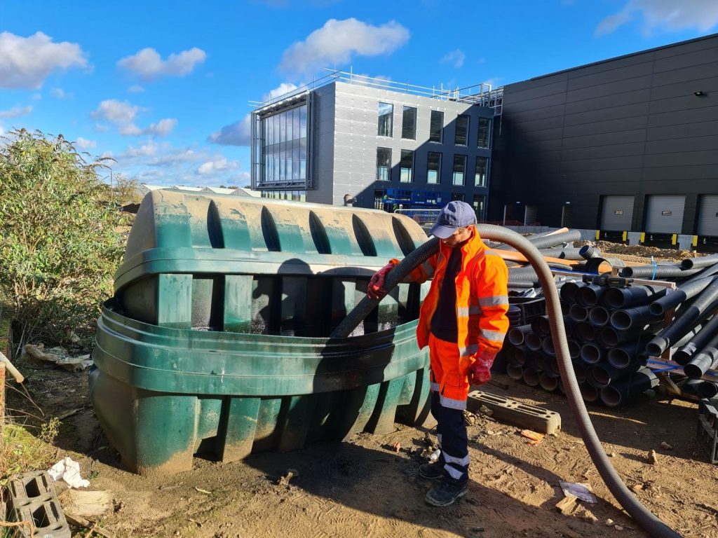 Technician cleaning an overfilled bunded plastic tank outdoors